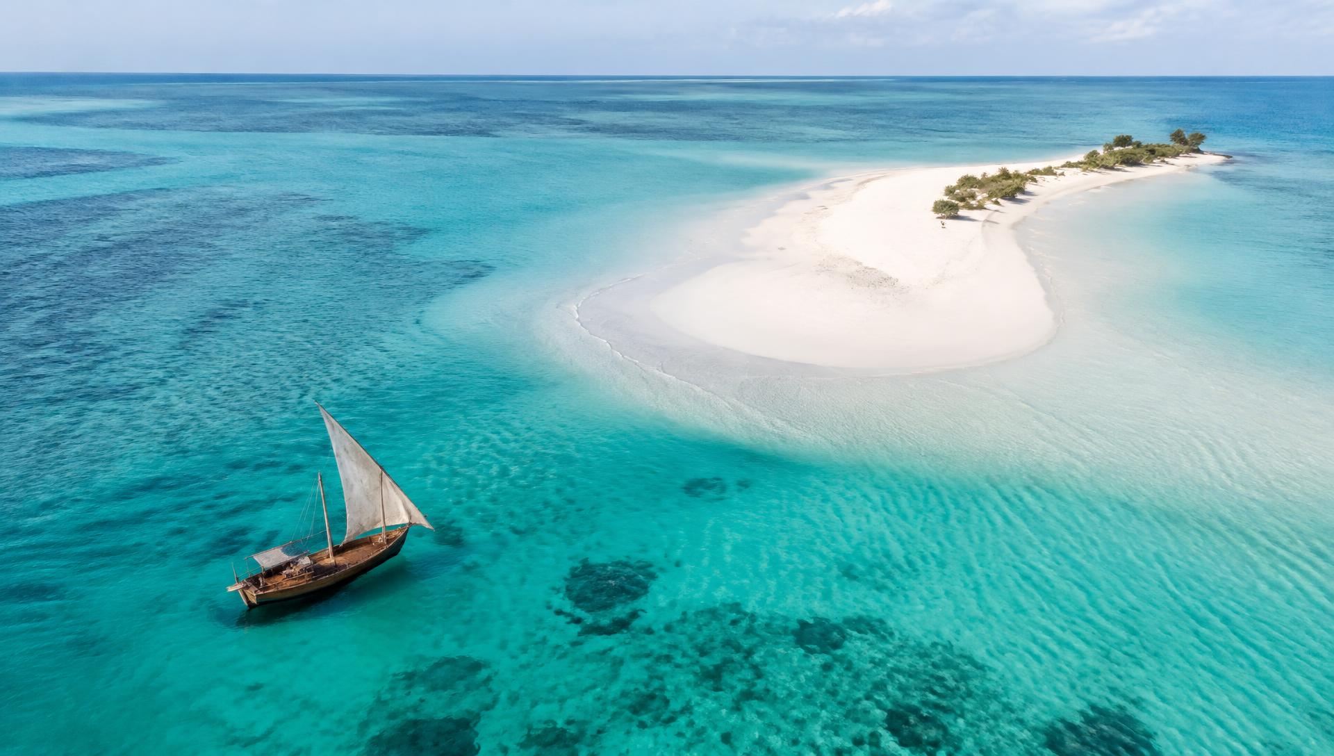 Dhow sailing beside a white sandbank in Zanzibar's turquoise lagoon